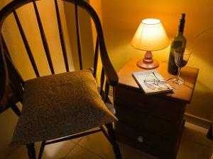 Pousada Jardim Secreto في تيريسوبوليس: طاولة مع كرسي ومصباح وزجاجة من النبيذ