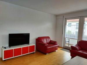 een woonkamer met 2 rode stoelen en een flatscreen-tv bij Gästehaus Walter in Hardt