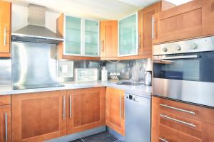 a kitchen with wooden cabinets and stainless steel appliances at The Lighthouse - Maison, 800m à pied du centre in Barneville-Carteret +6 photos