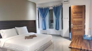 a bedroom with a white bed with blue curtains at Hemingway Cottage 海明威度假屋 in Semporna