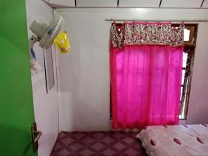a bedroom with a pink curtain and a window at Komodo homestay in Komodo