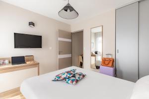 sypialnia z białym łóżkiem i telewizorem w obiekcie Appart'City Confort Angers w mieście Angers