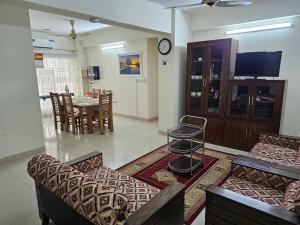 a living room with couches and a table and a tv at Sweet Rest Dhaka in Dhaka