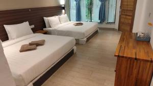 a hotel room with two beds and a wooden table at Hemingway Cottage 海明威度假屋 in Semporna