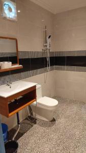a bathroom with a toilet and a sink and a mirror at Hemingway Cottage 海明威度假屋 in Semporna