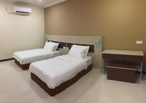 a hotel room with two beds and a desk at Hemingway Cottage 海明威度假屋 in Semporna