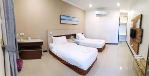 a hotel room with two beds and a television at Hemingway Cottage 海明威度假屋 in Semporna