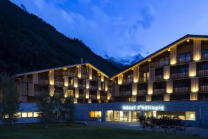 un bâtiment d'hôtel avec des montagnes en arrière-plan dans l'établissement Appartements de l'Héliopic, à Chamonix-Mont-Blanc