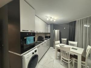 uma cozinha com armários brancos e uma mesa e cadeiras em Двустаен апартамент в центъра на Русе em Ruse