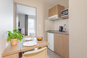 uma pequena cozinha com mesa e cadeiras num quarto em Appart'City Confort Angers em Angers