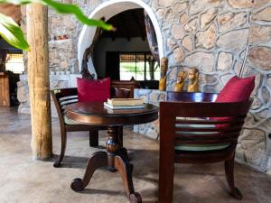 a table and chairs in a room with a stone wall at Oluchi Lodge in Guthrie