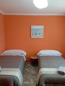 2 letti in una camera con parete arancione di A Casa do San Paio de Buscás a Ordes