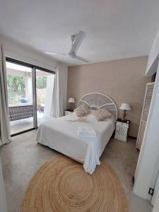 a bedroom with a white bed and a large window at AO Cottage in Petite Case Noyale