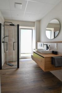 a bathroom with a sink and a shower and a mirror at Ammerhuus Boardinghomes in Edewecht