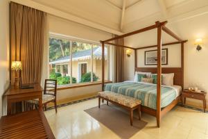 1 dormitorio con cama con dosel y escritorio en StayVista at Amara Villa Lux Collection with Private Pool, Gazebo, and Game Zone, en Alibaug