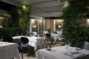 un restaurante con mesas blancas, sillas y plantas en Locanda La Gazzella, en Maranello