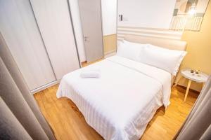 Cama blanca en habitación pequeña con mesa en KL Gateway Residences, en Kuala Lumpur