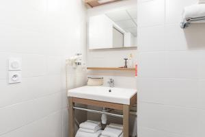 a white bathroom with a sink and towels at Appart'City Confort Angers in Angers
