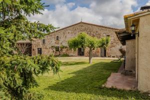 an old stone building with a tree in the yard at La Pahissa de Can Abras Casa Rural in Girona