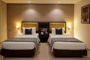 a hotel room with two beds and two lamps at Grand Continent Malleshwaram A Sarovar Portico Affiliate Hotel in Bangalore