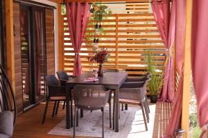 a table and chairs on a balcony with pink curtains at Iris Holiday Homes - Camping park Soline in Biograd na Moru