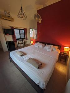a bedroom with a large white bed with a red wall at Goodtime Utopia Guesthouse in Koh Tao