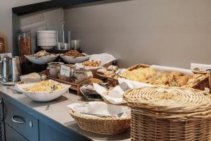a counter with many baskets of bread and other foods at Helvetia Hotel Munich City Center in Munich +17 photos