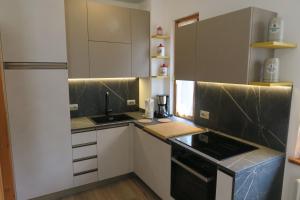 una piccola cucina con armadietti bianchi e una stufa nera di Casa Pippi a Ledro