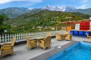 un patio con mesa y sillas junto a una piscina en juSTa Birding Resort & Spa - Best Dhauladhar View Resort, en Dharamshala