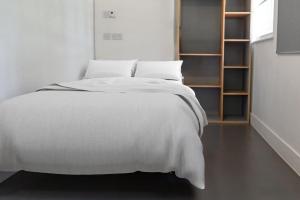 a bedroom with a white bed and a book shelf at For Students Only Ensuite Bedrooms with Shared Kitchen and Studios at The Old Fire Station in Birmingham in Birmingham