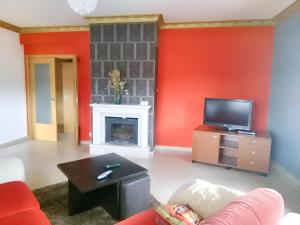 a living room with a fireplace and a tv at 2 bedrooms apartement with enclosed garden and wifi at Urqueira in Urqueira