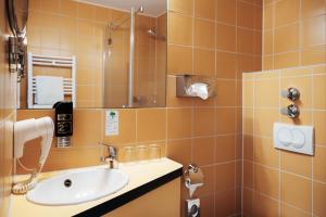 een badkamer met een wastafel en een douche bij Helvetia Hotel Munich City Center in München