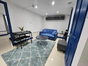 a living room with a blue couch and a table at Savers Apartment Close to Emirates Stadium! in London +4 photos