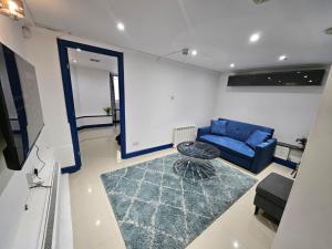 a living room with a blue couch and a tv at Savers Apartment Close to Emirates Stadium! in London