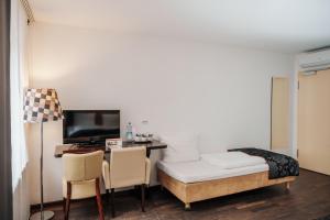 Habitación con escritorio, cama y TV. en Helvetia Hotel Munich City Center en Múnich