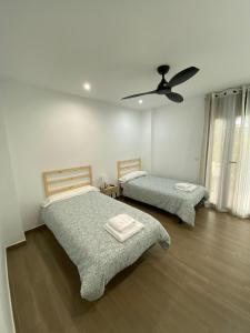 a bedroom with two beds and a ceiling fan at Casa Rural El Pino in Albacete