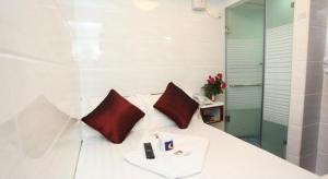 uma cama branca com duas almofadas vermelhas em Payless A2 Guest House em Hong Kong