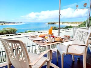 Hotel HS Milfontes Beach - Duna Parque Group في فيلا نوفا دو ميلفونتيس: طاولة طعام على شرفة مطلة على المحيط