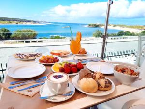uma mesa com comida para o pequeno almoço e vista para o oceano em Hotel HS Milfontes Beach - Duna Parque Group em Vila Nova de Milfontes