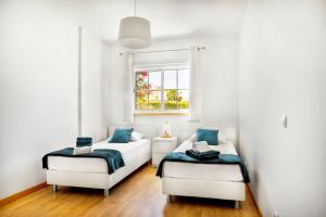 a living room with two beds and a window at Apartamento no Condomínio Baia Village com Piscina in Albufeira +30 photos