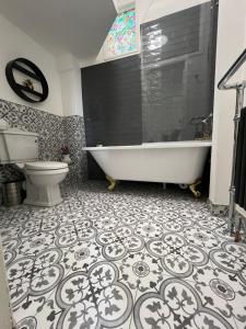 a bathroom with a tub and a toilet at Sea Spray Victorian Apartment in St. Leonards +36 photos