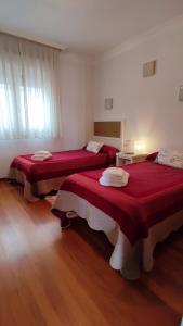 duas camas num quarto com lençóis vermelhos em ÁTICO Vilagarcía em Vilagarcía de Arousa