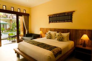 a bedroom with a bed and a living room with a patio at Mina Pelasa Hotel in Legian