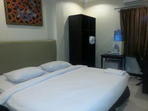 a bedroom with a large white bed with two pillows at Karaton Luwuk in Luwuk