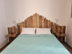 a bed with a wooden headboard in a room at Résidence Le Village Marin in Porto-Vecchio