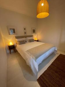 um quarto com uma grande cama branca e 2 candeeiros em House with a view em Alcácer do Sal