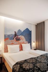 فندق هيلفيتيا مركز مدينة ميونيخ في ميونخ: غرفة فندق مع سرير مع لوحة على الحائط