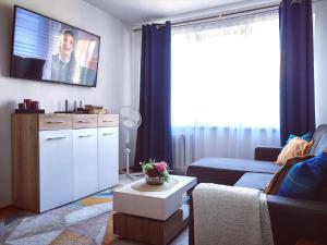 a living room with a couch and a tv on the wall at Krymo g. Lovely 2 room flat in Šiauliai, near Akropolis in Šiauliai +16 photos