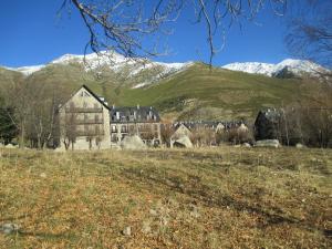 ein altes Haus auf einem Feld mit Bergen im Hintergrund in der Unterkunft Appartement au Pla de l'Ermita dans la Vallée de BoÏ , Pyrénées Catalanes in Pla de l'Ermita