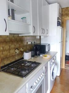 uma cozinha com armários brancos e um forno com placa de fogão em 3 bedrooms apartement with furnished terrace and wifi at Navalcarnero 5 km away from the slopes em Navalcarnero